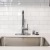 a kitchen sink with a white tiled wall behind it