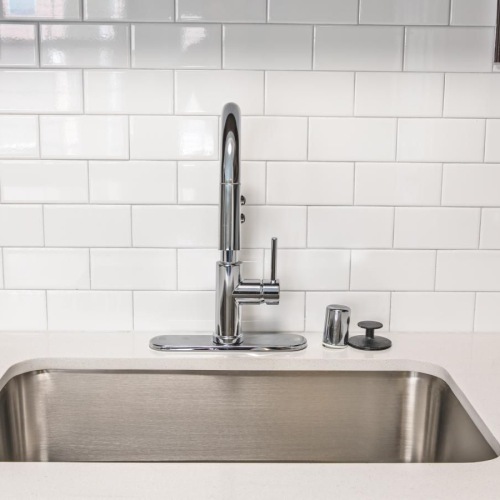 Beautiful kitchens with designer finishes a kitchen sink with a white tiled wall behind it